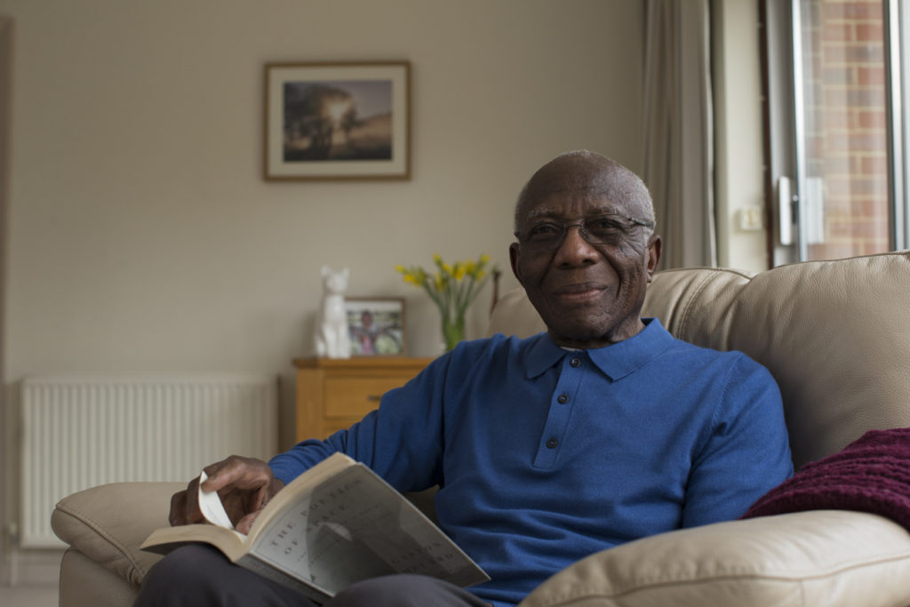 An older man is sitting down and reading a book