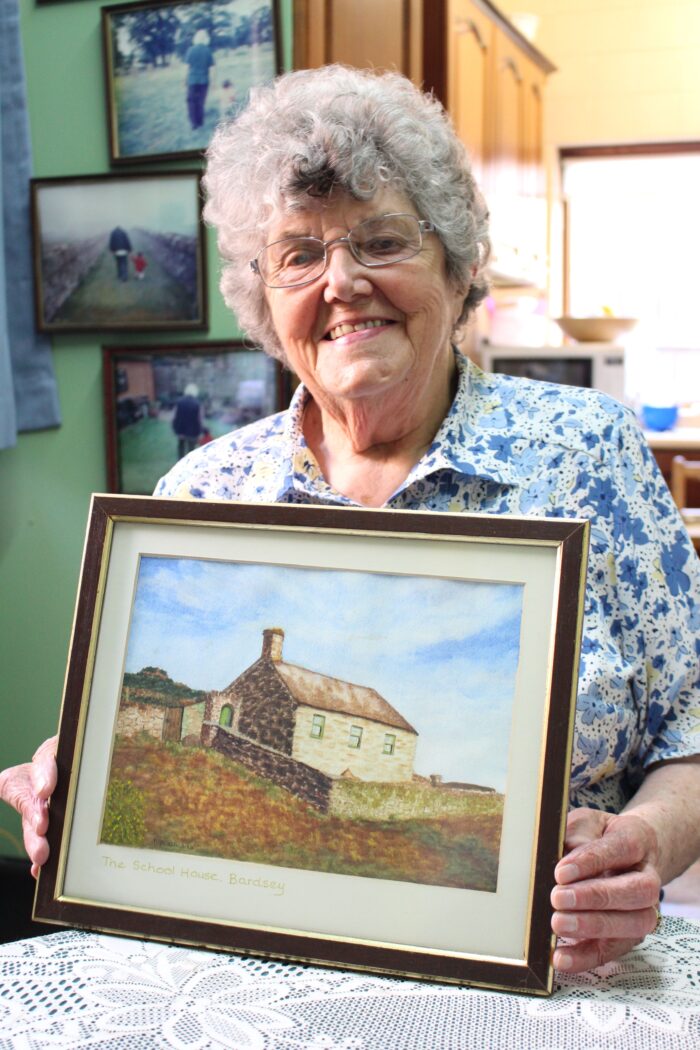 MMHS resident Gwen Watson with a painting of the school she used to attend on Bardsey Island.