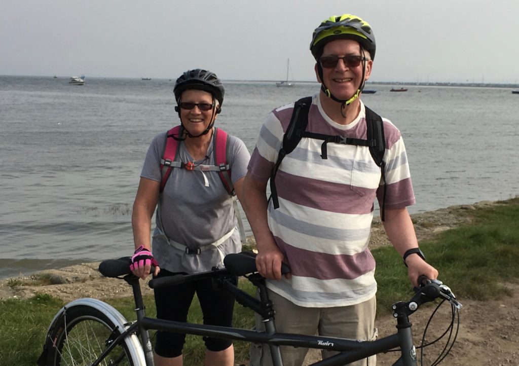 Norman and Jan are standing with their tandem by the coast